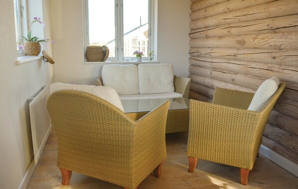 A cozy room with wicker furniture, a white sofa, and a view through a window.
