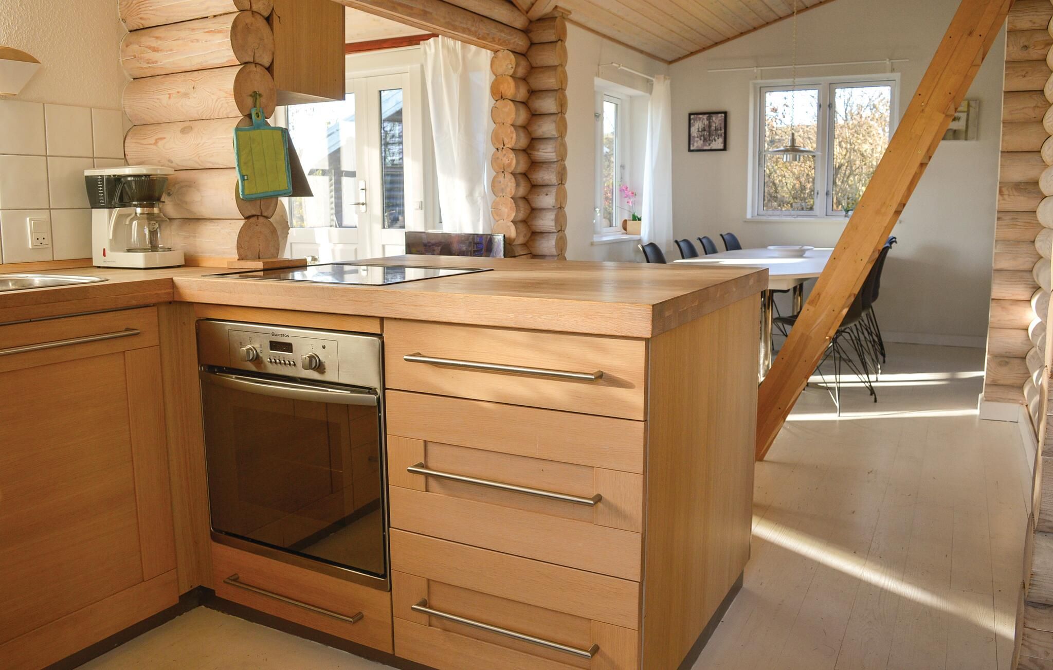 Una cocina con armarios de madera, horno empotrado y comedor con mesa y sillas.