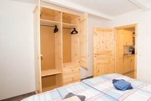 Ein Zimmer mit einem Bett, einem Holzschrank und einer kleinen Küchenzeile.