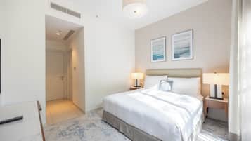 Een hotelkamer met een groot bed, twee bedlampen, een plafondlamp en een lijst met een abstract schilderij aan de muur.