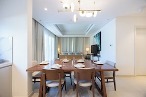 A modern dining area with a long table set for six, surrounded by chairs. - Bloomfields 3BR plus Maid Address Residences Fujairah (Fujairah)