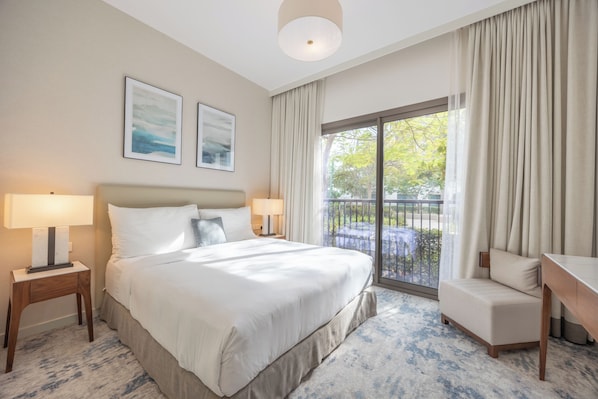 A hotel room with a large bed, two bedside lamps, a desk, and a view of the outdoors. - Bloomfields 3BR plus Maid Address Residences Fujairah (Fujairah)