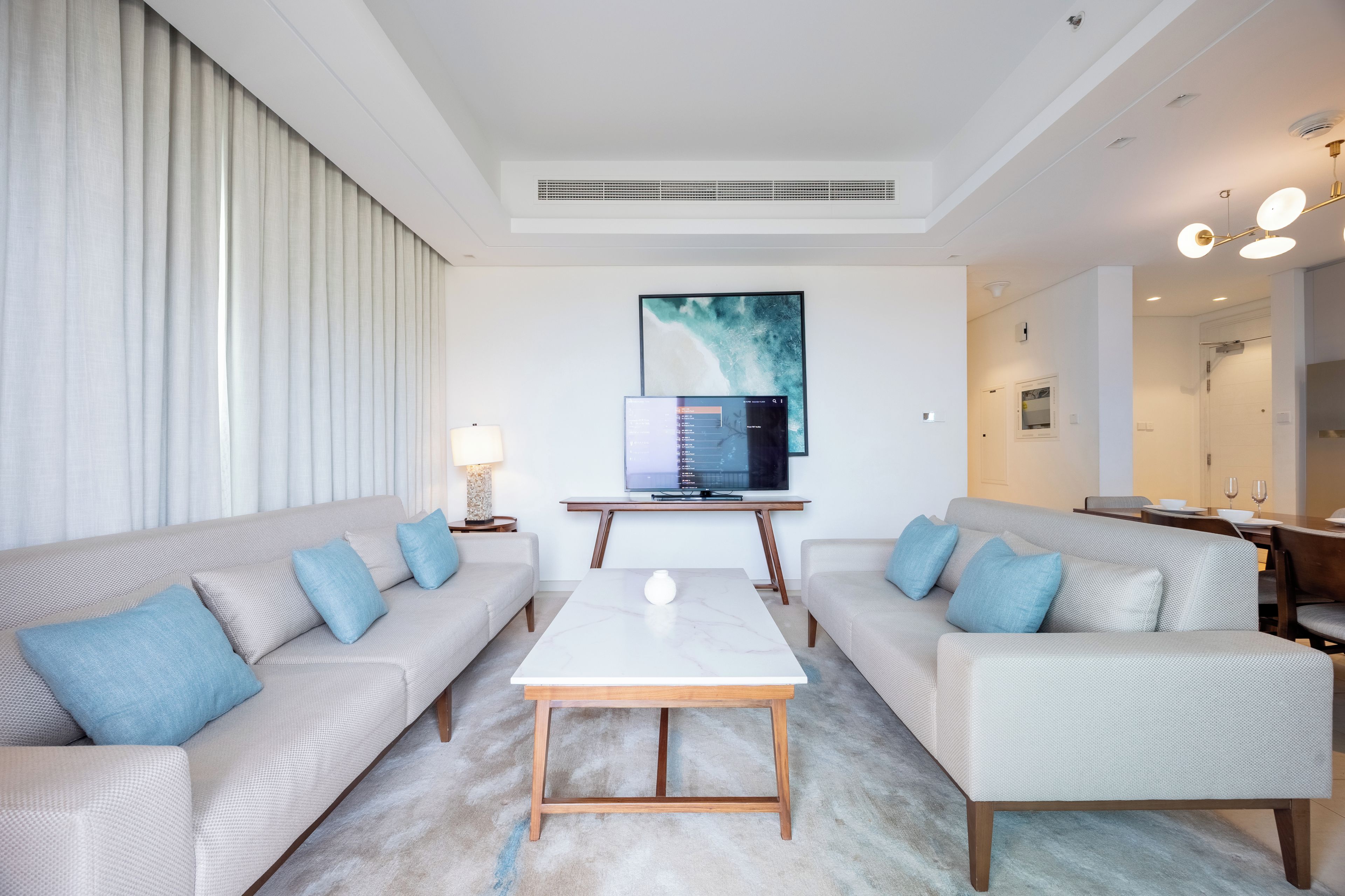 Een moderne woonkamer met twee banken, een salontafel en een flatscreen televisie aan de muur.