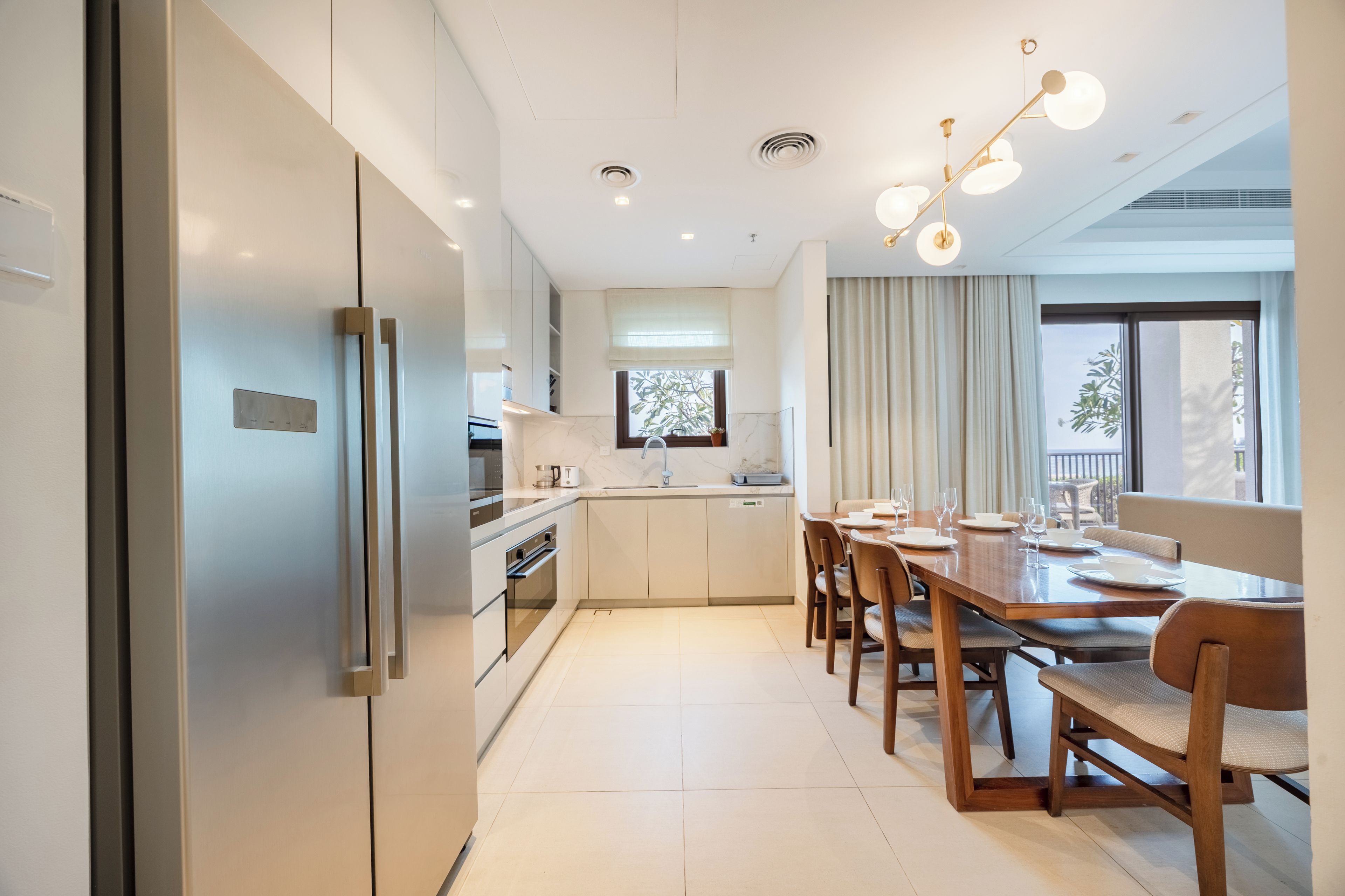 A modern kitchen with a dining area, stainless steel appliances, and a large window.