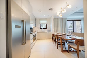 A modern kitchen with a dining area, stainless steel appliances, and a large window. - Bloomfields 3BR plus Maid Address Residences Fujairah (Fujairah)