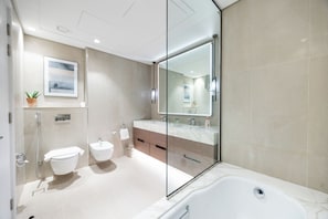 Et moderne badeværelse med bruseniche, badekar, toilet og håndvask.