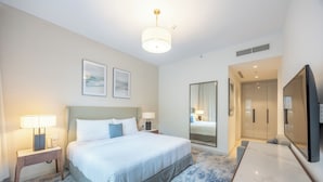 Een hotelkamer met een bed, nachtkastjes, een flatscreen televisie, een grote spiegel en een deur naar de badkamer.