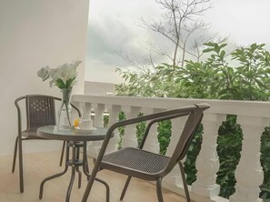 A balcony with two chairs, a small table, and a vase with flowers. - De Jehans Boutique Hotel (Cilimus)
