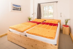 A double bed with a wooden frame, a window with curtains, a small bedside table with a lamp, and a framed picture on the wall. - on the Baltic Sea - semi-detached house (Rerik)