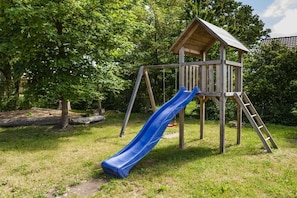 Une structure de jeu en bois, dotée d’un toboggan et d’une échelle d’escalade.