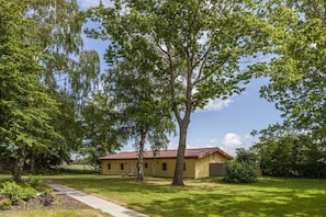A single-story building with a red roof, surrounded by green trees and grass. - on the Baltic Sea - semi-detached house (Rerik)