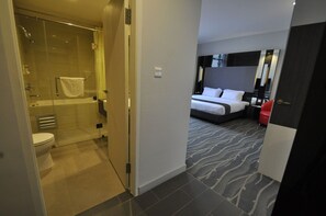 A hotel room with a shower, toilet, bed, and a red chair. - Dreamtel Jakarta (Jakarta)