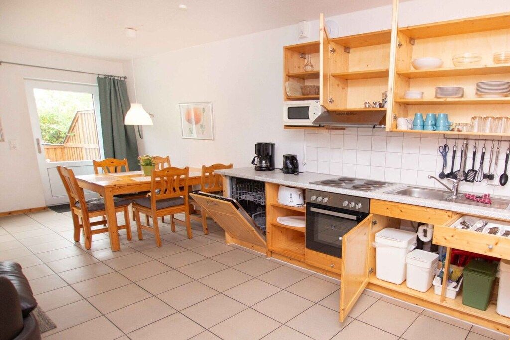 Una cucina compatta con mobili in legno, forno integrato e un'area pranzo con tavolo e sedie.