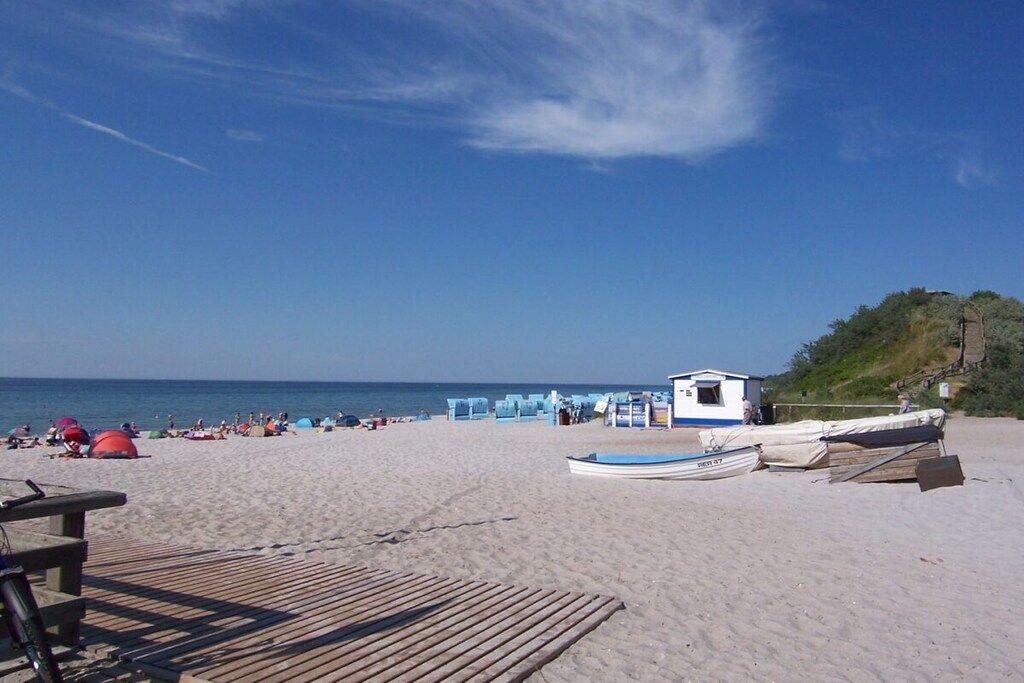 Une plage avec une terrasse en bois, un petit bateau et un poste de surveillance des sauveteurs.