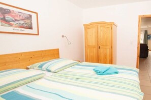 A bedroom with a bed, a wooden wardrobe, and a framed picture on the wall. - Terraced house, 60 sqm, 2 bedrooms (Rerik)