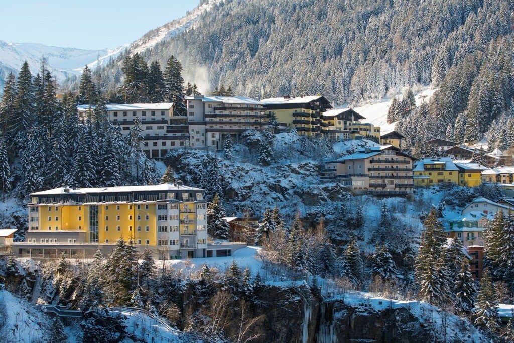 A hotel complex with multiple buildings, surrounded by snow-covered trees and mountains.
