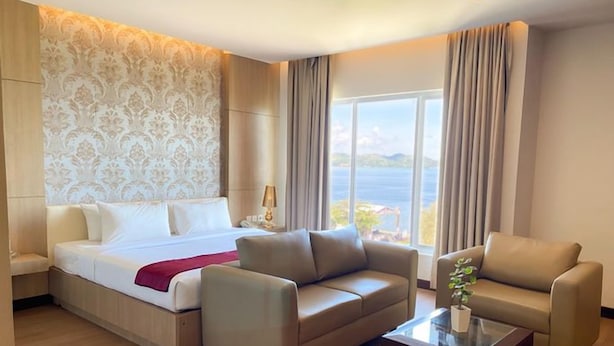 Habitación de hotel con una cama, dos sofás, una mesa de centro y vistas al mar.