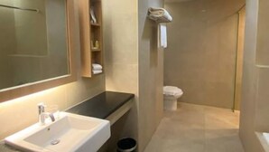 Un baño estrecho con lavamanos, espejo y zona de ducha.