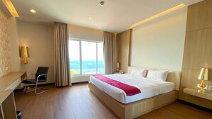 Habitación de hotel con una cama grande, un escritorio, una silla y vista al mar.
