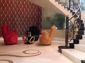 A modern interior with a patterned wall, a staircase, and a red chair.