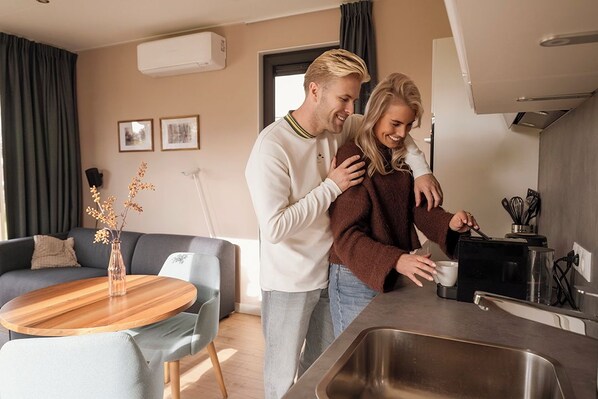 Et moderne køkken med indbygget ovn, vask og kaffemaskine.