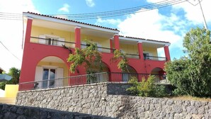 Un edificio de dos pisos con base de piedra, balcones y fachada roja y amarilla.