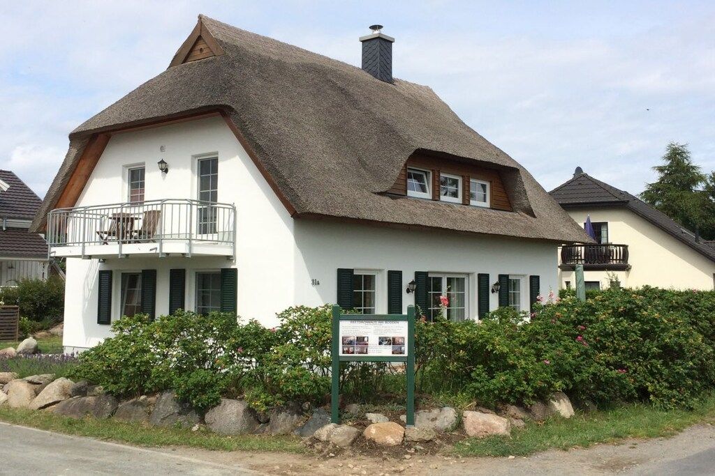Un bâtiment traditionnel avec un toit de chaume, un balcon et une enseigne devant l’entrée.