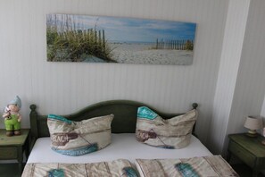 A bedroom with a beach-themed bedspread, pillows, and a wall-mounted painting of a beach scene. - Holiday apartment with 1 bedroom (Sassnitz)