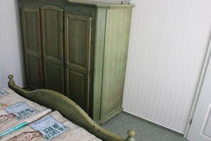 A room with a bed, a green wardrobe, and a white door. - Holiday apartment with 1 bedroom (Sassnitz)