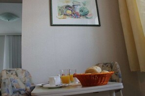 A breakfast setup with a basket of bread, two cups, and a glass of orange juice on a table. - Holiday apartment with 1 bedroom (Sassnitz)