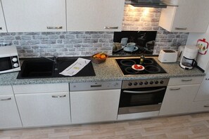 A modern kitchen with a granite countertop, a built-in oven, a microwave, and a coffee maker. - Holiday apartment with 1 bedroom (Sassnitz)