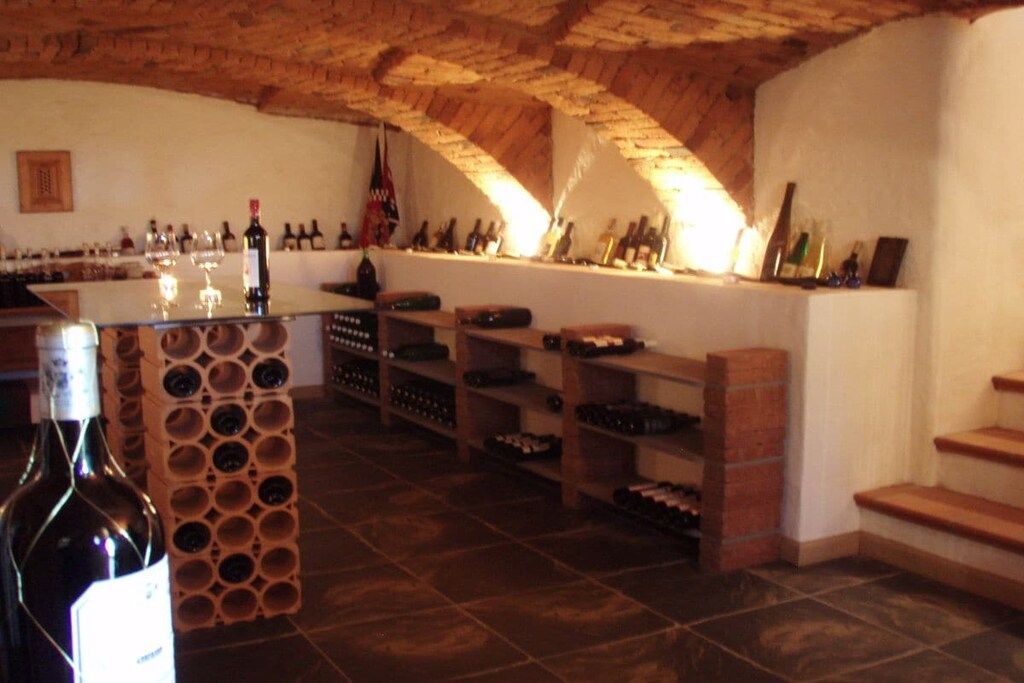 An interior with a wine rack, shelves with bottles, and a brick wall.