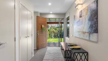 A hallway with a wooden door, a bench, and a wall-mounted abstract painting.