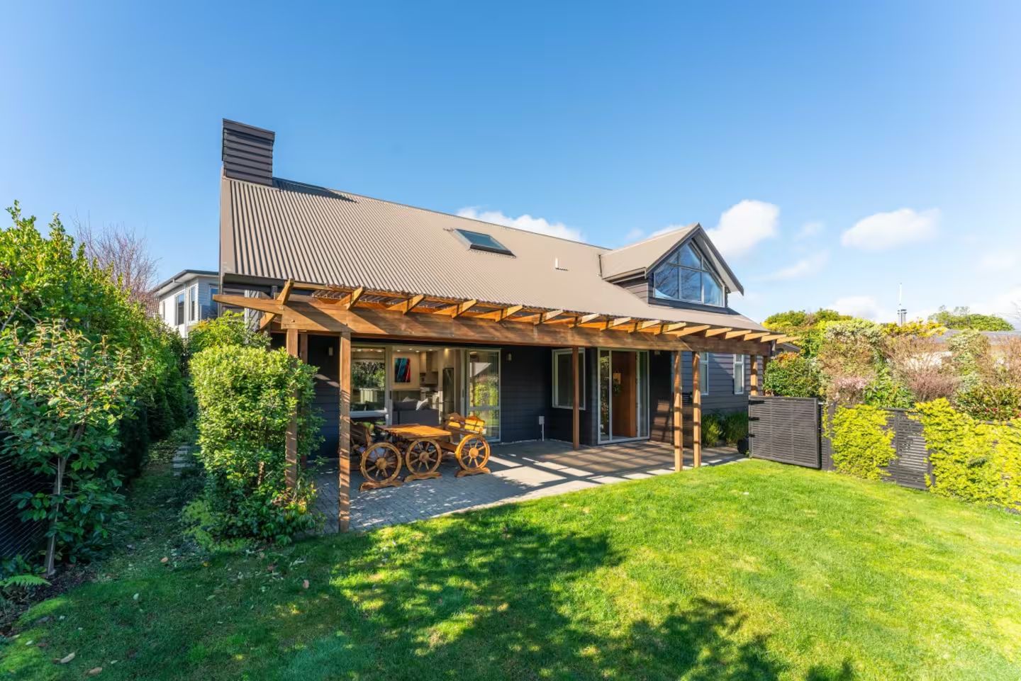 Ein modernes Haus mit überdachter Terrasse, sichtbarer Garage und gepflegtem Rasen.