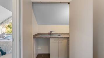A compact kitchen with a sink, cabinets, and a window overlooking a garden.