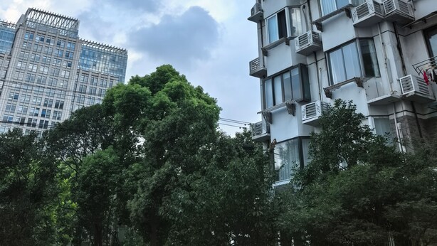 A high-rise building with multiple balconies and windows, surrounded by trees and under a partly cloudy sky. - Innocondo Extended Stay Jing'an Changde Road (Shanghai)