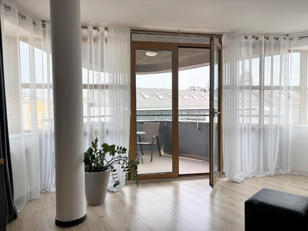 A room with a sliding glass door leading to an outdoor balcony. There is a potted plant on the floor.