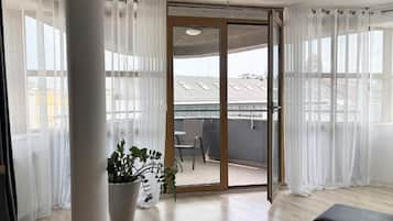 A room with a sliding glass door leading to an outdoor balcony. There is a potted plant on the floor.