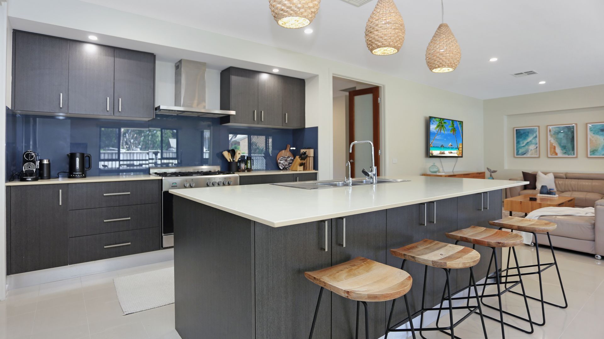A modern kitchen with a large island, bar stools, and a dining area with a sofa.
