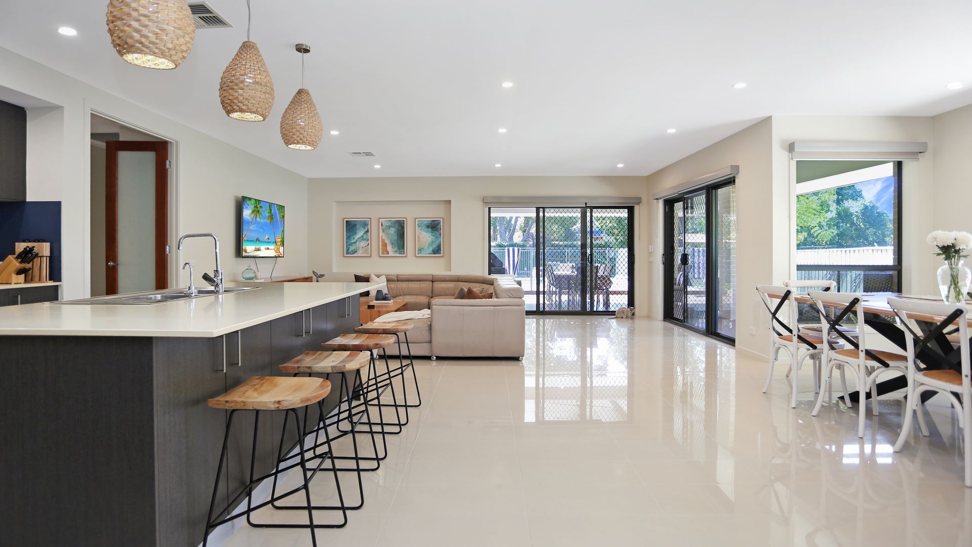 A modern kitchen with a central island, bar stools, and pendant lighting.