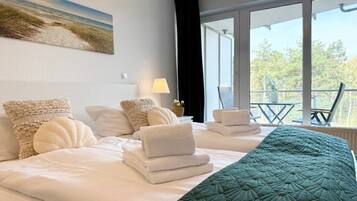 A hotel room with a bed, pillows, a quilt, a window, and a view of the outdoors.