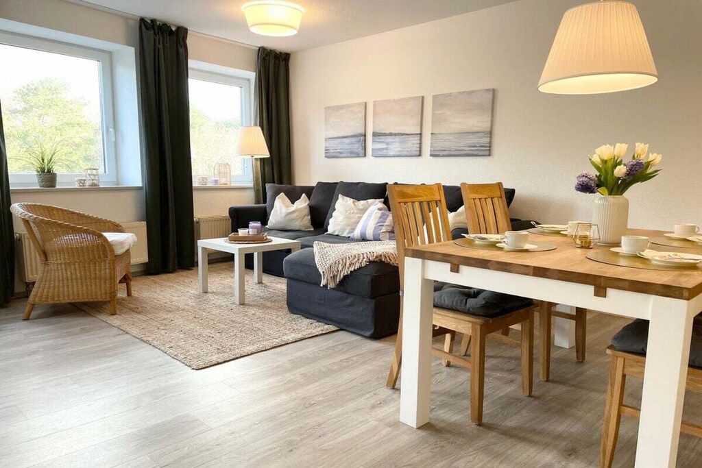 A modern living room with a sofa, chairs, a dining table, and artwork on the wall.