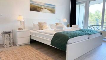 A bedroom with a bed, bedside tables, lamps, a rug, and a window with a view.
