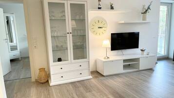 A modern living room with a white cabinet, a flat-screen TV, and a wall clock.