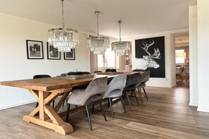 A dining area with a wooden table, grey upholstered chairs, and crystal chandeliers. - Romantic Chalet Neuastenberg (Winterberg)