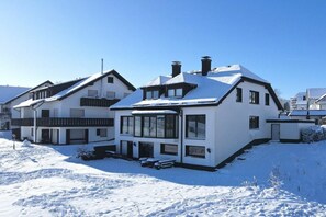 A two-story house with a snow-covered roof and a large window on the ground floor. - Romantic Chalet Neuastenberg (Winterberg)