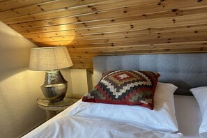 A room with a bed, a nightstand, a lamp, and a patterned pillow. - Romantic Chalet Neuastenberg (Winterberg)