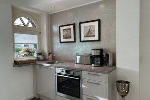A kitchen with a built-in oven, a coffee maker, and a wine glass on the counter. - Romantic Chalet Neuastenberg (Winterberg)