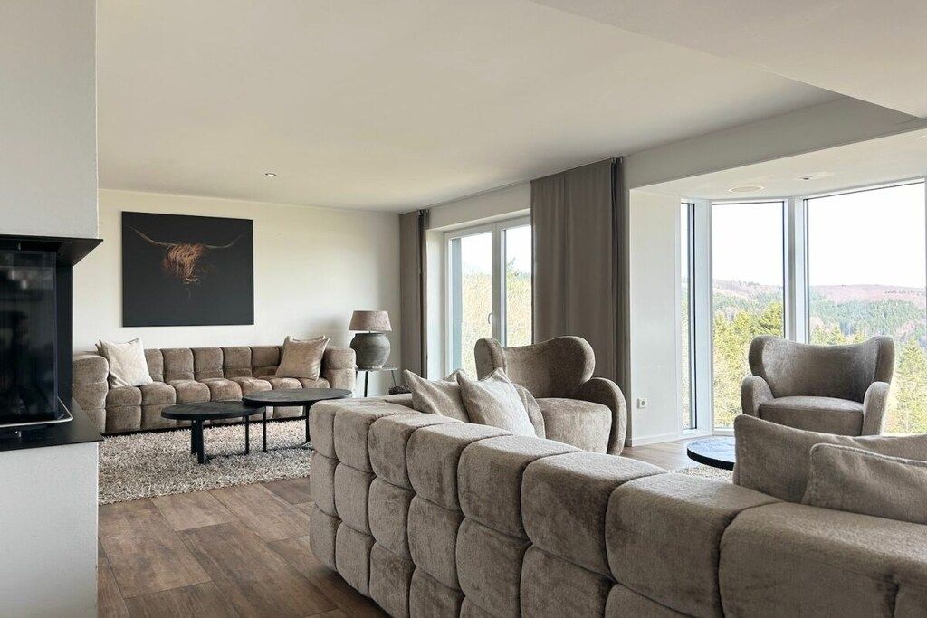 Ein modernes Wohnzimmer mit einer Eckcouch, einem Couchtisch und einem Flachbildfernseher.