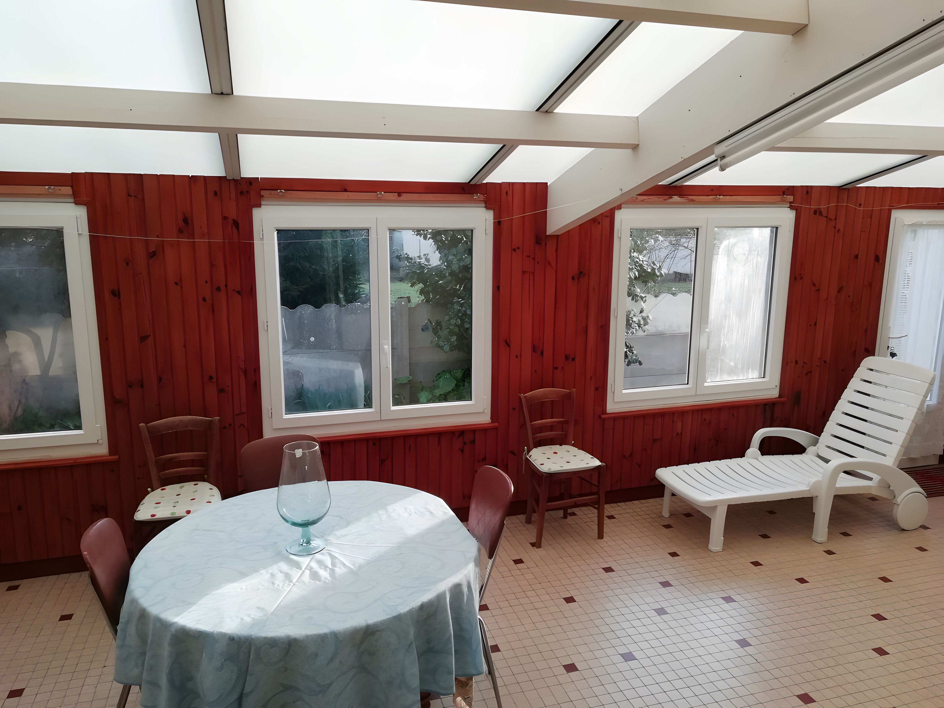 A room with a round table, chairs, and a glass.